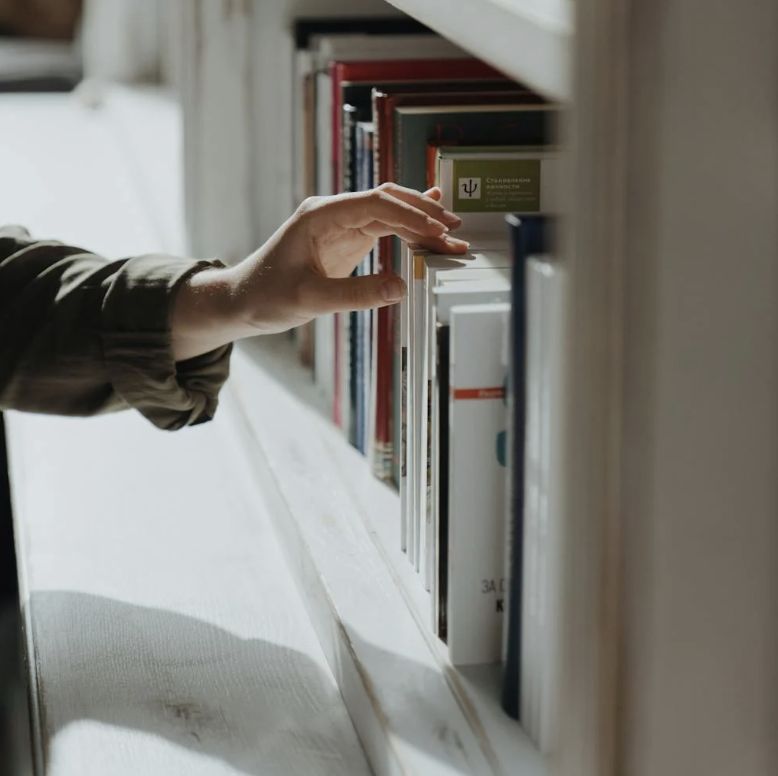 hand pulling out book from shelf